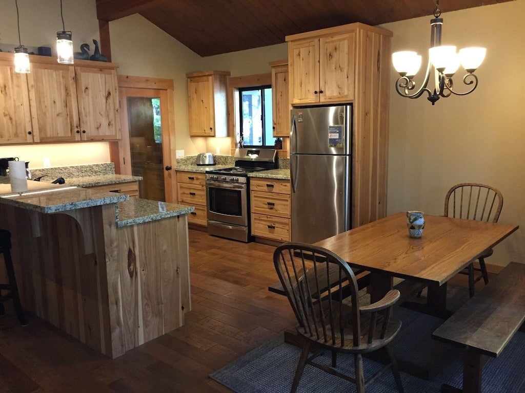 Dining table and remodeled kitchen with stainless appliances.
