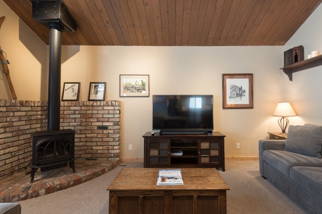 Living room with gas stove, TV, and warm Tahoe cabin character.