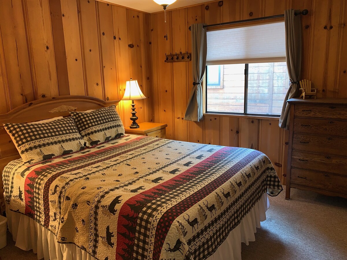 Middle bedroom with queen bed, dresser, and window.