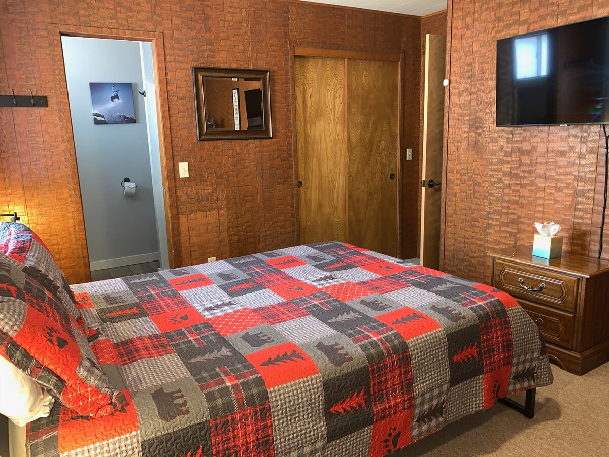 Back bedroom with queen bed and wall-mounted TV.