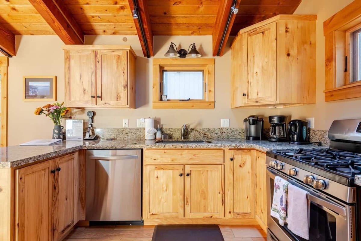Kitchen sink, range, and prep space with warm wood finishes.