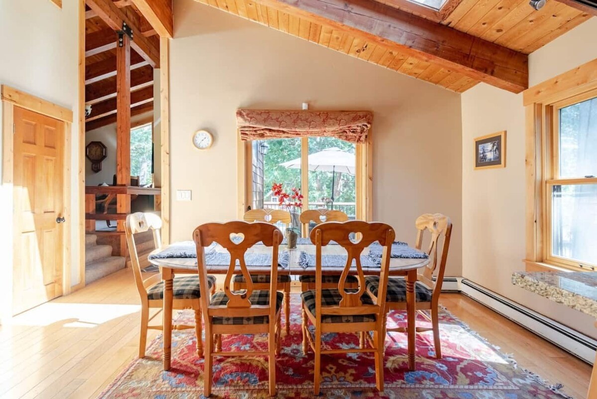 Dining table with natural light and vaulted wood ceilings nearby.